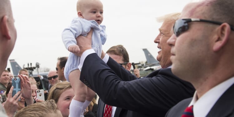 President Donald Trump holds a baby in a crowd