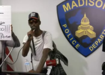 A demonstrator interrupts a police briefing on July 23, 2026, in Madison, Wisconsin.