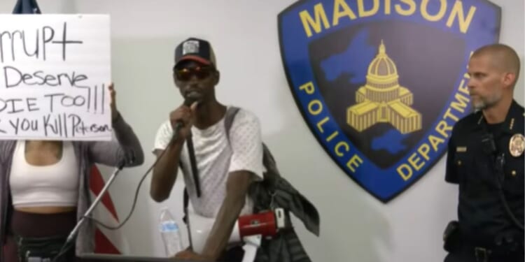 A demonstrator interrupts a police briefing on July 23, 2026, in Madison, Wisconsin.