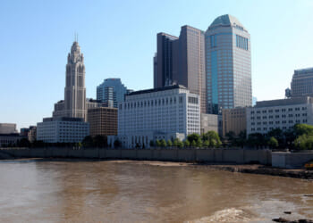 Downtown city skyline of Columbus, Ohio with river and blue sky in the background.
