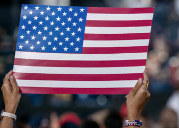 WASHINGTON, DISTICT OF COLUMBIA, UNITED STATES - 2026/06/24: A woman reacts while holding an American flag sign during the kickoff celebration for the Great American State Fair on the National Mall. The fair, held as part of celebrations marking the 250th anniversary of U.S. independence, will run from June 24 through July 10. (Photo by Probal Rashid/LightRocket via Getty Images)