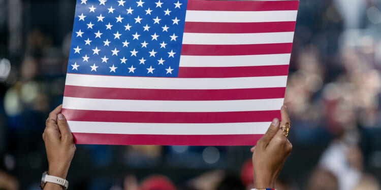 WASHINGTON, DISTICT OF COLUMBIA, UNITED STATES - 2026/06/24: A woman reacts while holding an American flag sign during the kickoff celebration for the Great American State Fair on the National Mall. The fair, held as part of celebrations marking the 250th anniversary of U.S. independence, will run from June 24 through July 10. (Photo by Probal Rashid/LightRocket via Getty Images)