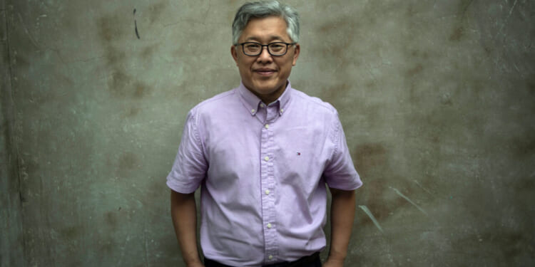 Pastor Ezra Jin stands against a grey background.