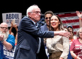 Sen. Bernie Sanders greets Rep. Alexandria Ocasio-Cortez at The People v. The Powerful rally at the Detroit Opera House on July 18, 2026, in Detroit, Michigan.