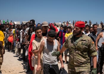 Migrants wait to receive water on the beach next to the CETI on Aug. 2, 2026, in Ceuta, Spain.