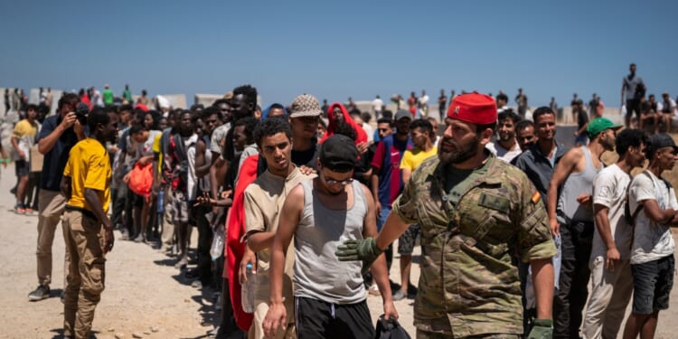 Migrants wait to receive water on the beach next to the CETI on Aug. 2, 2026, in Ceuta, Spain.