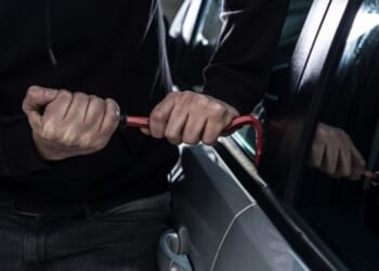 A man breaks into a car with a crowbar.