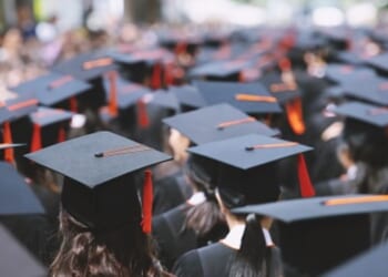 Students stand at a graduation ceremony.