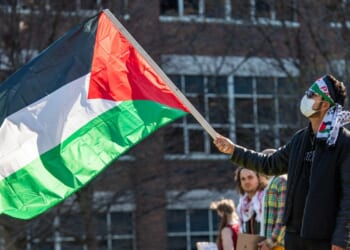 A person waves a Palestinian flag as pro-Palestinian protesters gather at an encampment set up at Northeastern University in Boston, Massachusetts, on April 25, 2024.