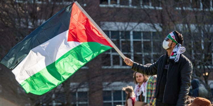 A person waves a Palestinian flag as pro-Palestinian protesters gather at an encampment set up at Northeastern University in Boston, Massachusetts, on April 25, 2024.