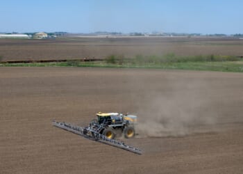 In an aerial view, a farmer applies a pre-emergent herbicide to a recently-planted corn field on May 7, 2026, near Mason City, Iowa.