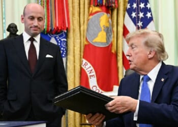 President Donald Trump holds binders containing two executive orders he signed Thursday targeting birthright citizenship for some individuals and "birth tourism." With him is White House Deputy Chief of Staff Stephen Miller.