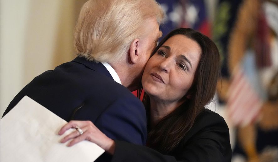 President Donald Trump hugs Allyson Phillips, mother of Laken Riley, before he signs the Laken Riley Act in the East Room of the White House, Wednesday, Jan. 29, 2025, in Washington. (AP Photo/Alex Brandon)