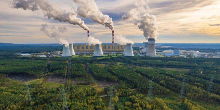 A coal-powered plant in Bełchatów, Poland pumps plumes of smoke into the air above the facility.