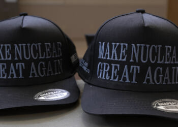 Two black snapback hats with the words MAKE NUCLEAR GREAT AGAIN embroidered in white on the front, placed side by side on a surface.