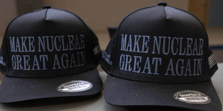 Two black snapback hats with the words MAKE NUCLEAR GREAT AGAIN embroidered in white on the front, placed side by side on a surface.