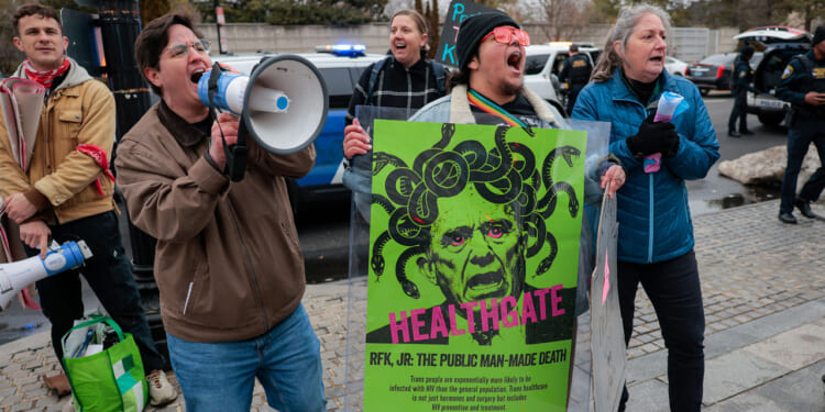 Protesters with Gender Liberation Movement and ACT UP demonstrate outside the Department of Health and Human Services while protesting the Trump administration’s plan to cut federal funding to clinics providing care for transgender youth on February 17, 2026 in Washington, DC.
