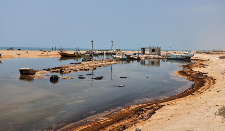 Oil residue lines the shore near fishing boats on Qeshm Island, Iran, Thursday, Aug. 13, 2026, amid ongoing wartime attacks on vessels and infrastructure in and around the Strait of Hormuz, though the spill's source has not been independently determined. (Amirhosein Khorgooi/ISNA via AP)