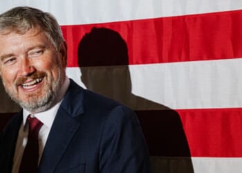 Former Rep. Thomas Massie smiles at crowd as he stands near an American flag on May 19, 2026.