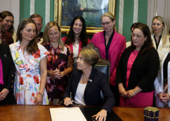 Massachusetts Governor Maura Healey turns to the women gathered behind her after signing a bill prioritizing patient access to care to strengthen abortion protections in Massachusetts at the State House on August 10, 2026. (Photo by Jessica Rinaldi/The Boston Globe via Getty Images)