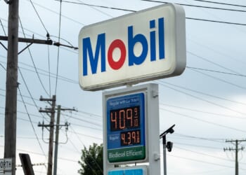 A Mobil gas station sign displays gas prices: Regular at $4.09 per gallon and Diesel at $4.99 per gallon. Power lines and a cloudy sky are visible in the background.