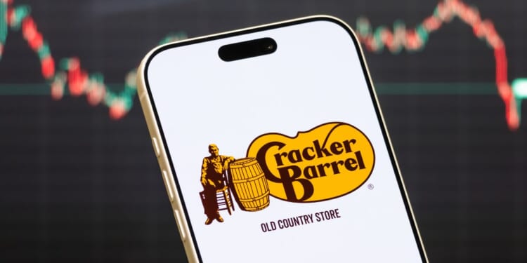 A Cracker Barrel logo displayed on a phone in front of a stock market chart.