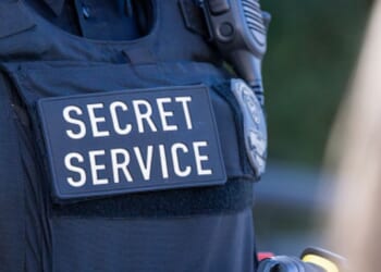 A Secret Service agent displays the text on his black vest.