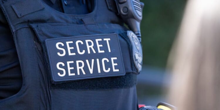 A Secret Service agent displays the text on his black vest.