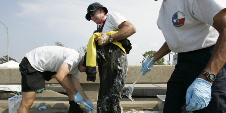 Eddie Mathison of the Texas Task Force 1 Water Search and Rescue Team from Houston, Texas, is scrubbed down with bleach and soap after a day of running boat rescues throughout downtown New Orleans in the aftermath of Hurricane Katrina, on Sept. 5, 2005.