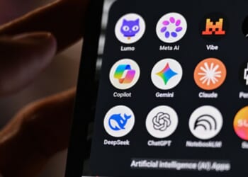 A phone screens displays AI apps in a dimly illuminated space.