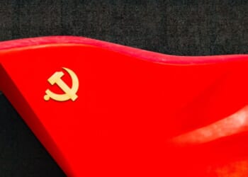 An object depicting a hammer and sickle icon on the edge is pictured ahead of a black surface.