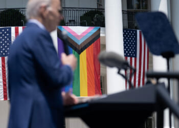 US President Joe Biden speaks during a Pride celebration on the South Lawn of the White House in Washington, DC, on June 10, 2023. Trans flag flying next to American flags.