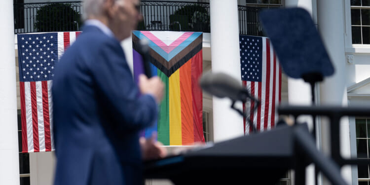 US President Joe Biden speaks during a Pride celebration on the South Lawn of the White House in Washington, DC, on June 10, 2023. Trans flag flying next to American flags.