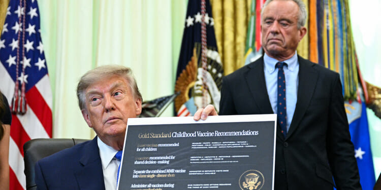 A man in a suit holds up a document titled Gold Standard Childhood Vaccine Recommendations while another man stands behind him in an official-looking room with flags in the background.