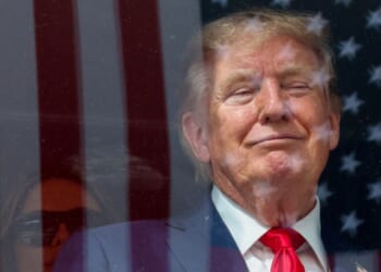 An American flag is reflected off bulletproof glass as President Donald Trump watches the end of the NTT Indycar Series Sunday in Washington, D.C.