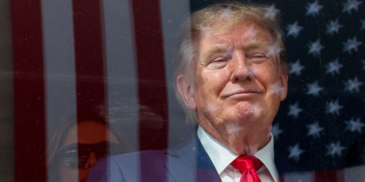 An American flag is reflected off bulletproof glass as President Donald Trump watches the end of the NTT Indycar Series Sunday in Washington, D.C.