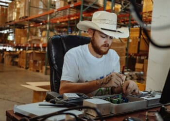 A man wearing a cowboy hat sits at a table and works.