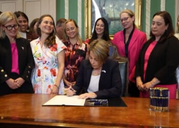 Massachusetts Governor Maura Healey signed the bill, surrounded by grinning, giggling females.