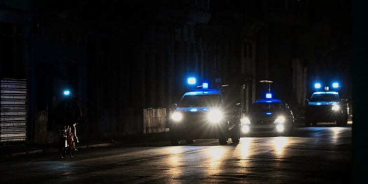 Police lights flash on a dark road in Havana on March 21, 2026.