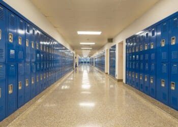 A typical empty school hallway with royal blue metal lockers along both sides of the hallway.