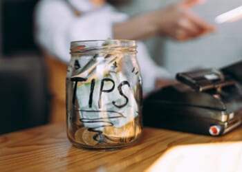 A tip jar sits full on a cashier counter.