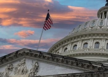 The Capitol Building stands while the American flag flies at dusk.