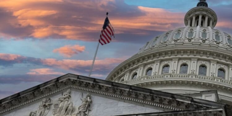 The Capitol Building stands while the American flag flies at dusk.