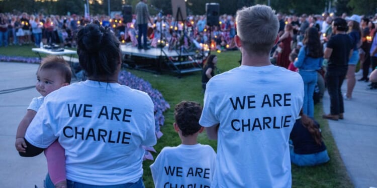 People wear t-shirts reading "We Are Charlie" as they pay their respects during a candlelight vigil for right-wing activist Charlie Kirk at a makeshift memorial at Memorial Park in Provo, Utah, on Sept. 12, 2025, after he was shot during a public event at Utah Valley University.