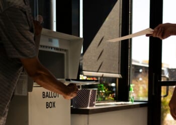 A voter drops a ballot into a ballot box at the Minneapolis Elections & Voter Services building on Sept. 20, 2024. in Minneapolis, Minnesota. The Department of Justice indicted 10 people accused of voting illegally in 2022, 2024, and 2026.