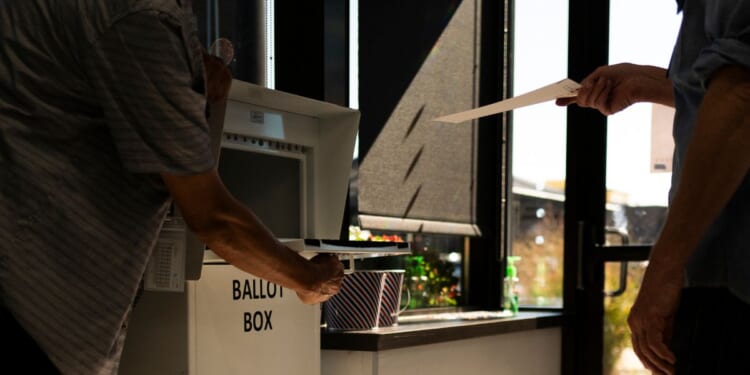 A voter drops a ballot into a ballot box at the Minneapolis Elections & Voter Services building on Sept. 20, 2024. in Minneapolis, Minnesota. The Department of Justice indicted 10 people accused of voting illegally in 2022, 2024, and 2026.