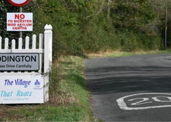 A sign for the village of Piddington, England, is pictured next to another saying 'No to Bicester MOD asylum centre,' in reference to a government plan to house some 1,200 male asylum seekers nearby.