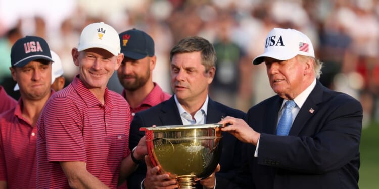 Captain Brandt Snedeker of the U.S. team lifts the trophy after their 17-13 win during the trophy ceremony as President Donald Trump looks on following the Sunday's Singles on day four of the Presidents Cup 2026 at Medinah Country Club on Sept. 27, 2026, in Medinah, Illinois.