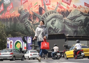 A woman crosses as motorists drive past an anti-US billboard at Enghelab Square in Tehran on Sept. 2.