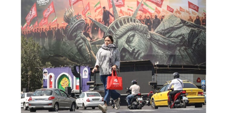 A woman crosses as motorists drive past an anti-US billboard at Enghelab Square in Tehran on Sept. 2.